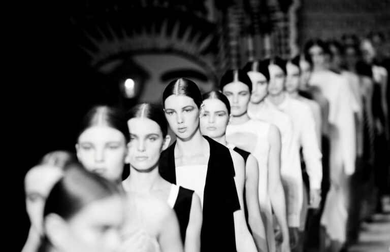 High contrast black and white image of models walking down the fashion runway.